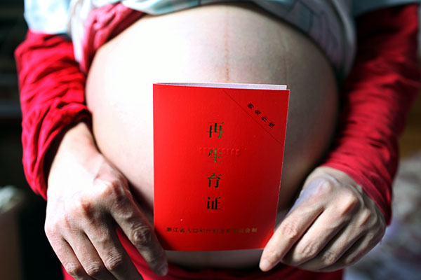 A birth approval certificate for a second child is shown by a pregnant woman in Quzhou, Zhejiang province, in April last year.[XU YUANCHANG/CHINA DAILY]