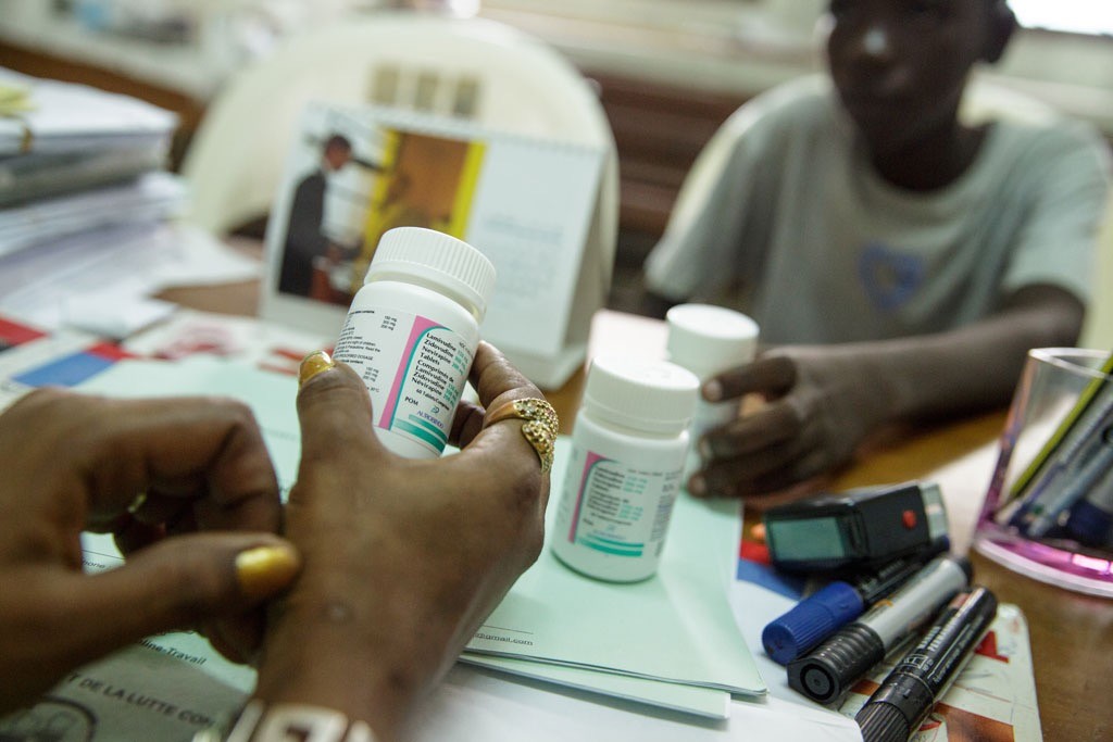 In Côte d’Ivoire, a counsellor from UNICEF partner NGO Femme Active, instructs an adolescent boy, diagnosed with HIV in 2012, on how to take his antiretroviral (ARV) medication correctly. Photo: UNICEF/Olivier Asselin